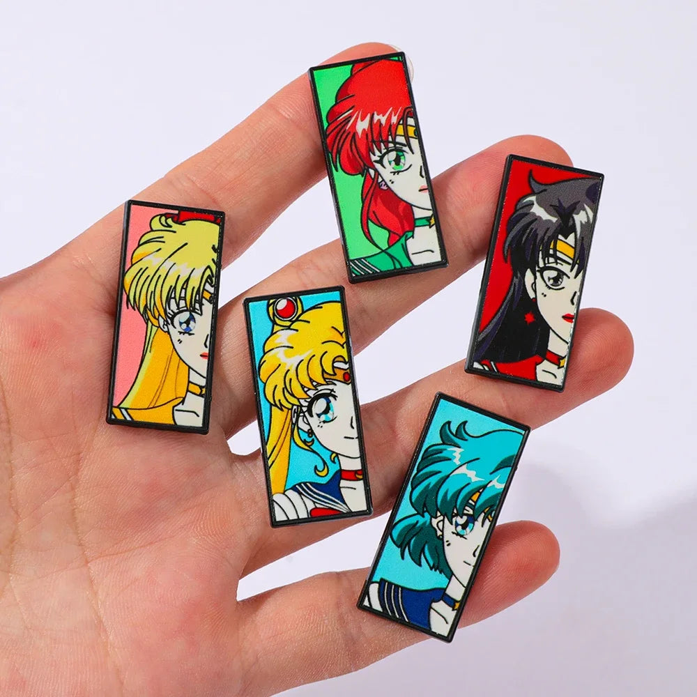 Hand holding five colorful Sailor Moon anime-style character 5-piece enamel lapel pins designs on a white background.