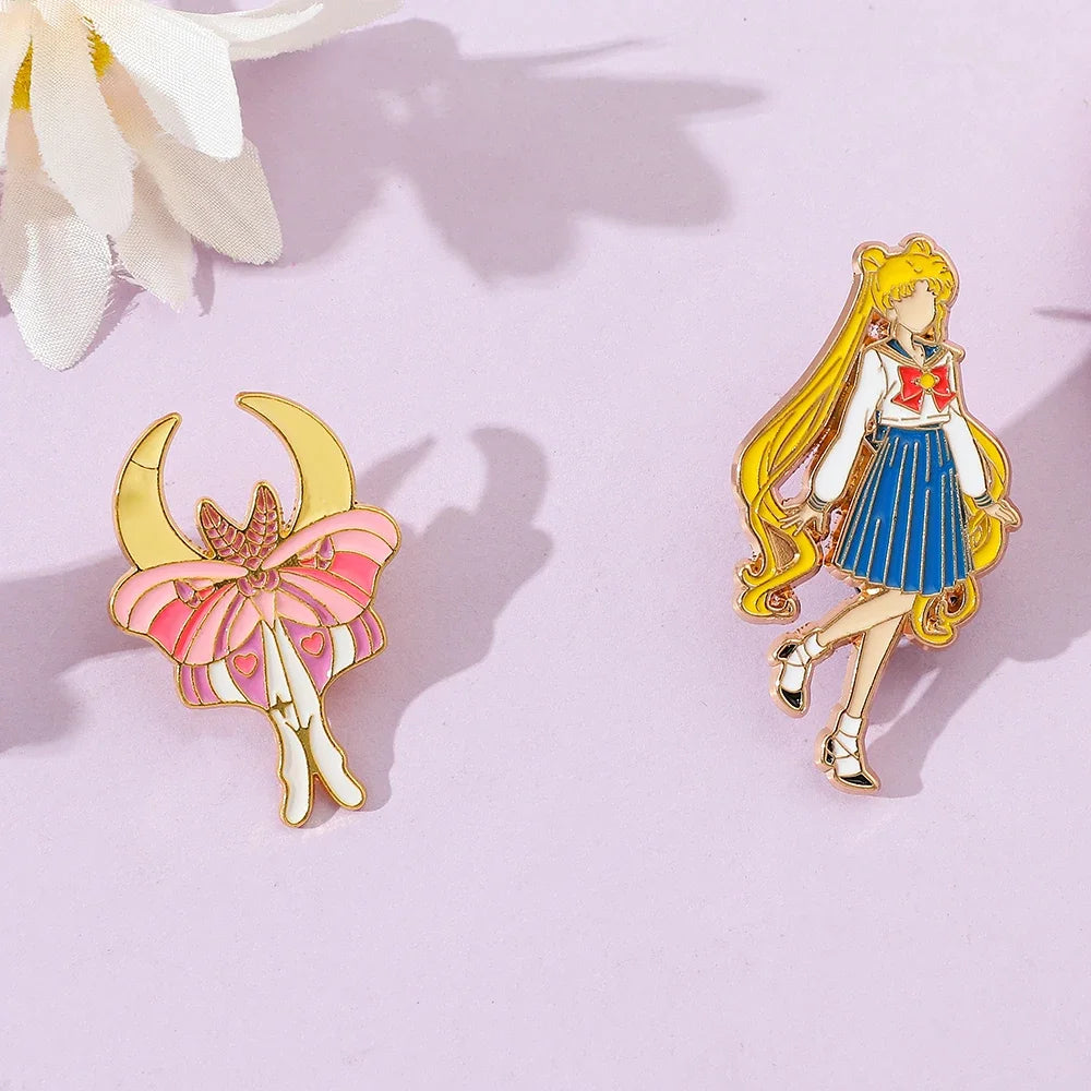 Two Sailor Moon enamel pins on a pink background with white flowers. 
