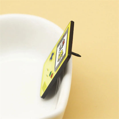 Small electronic device with a screen on top of a white cup against a beige background